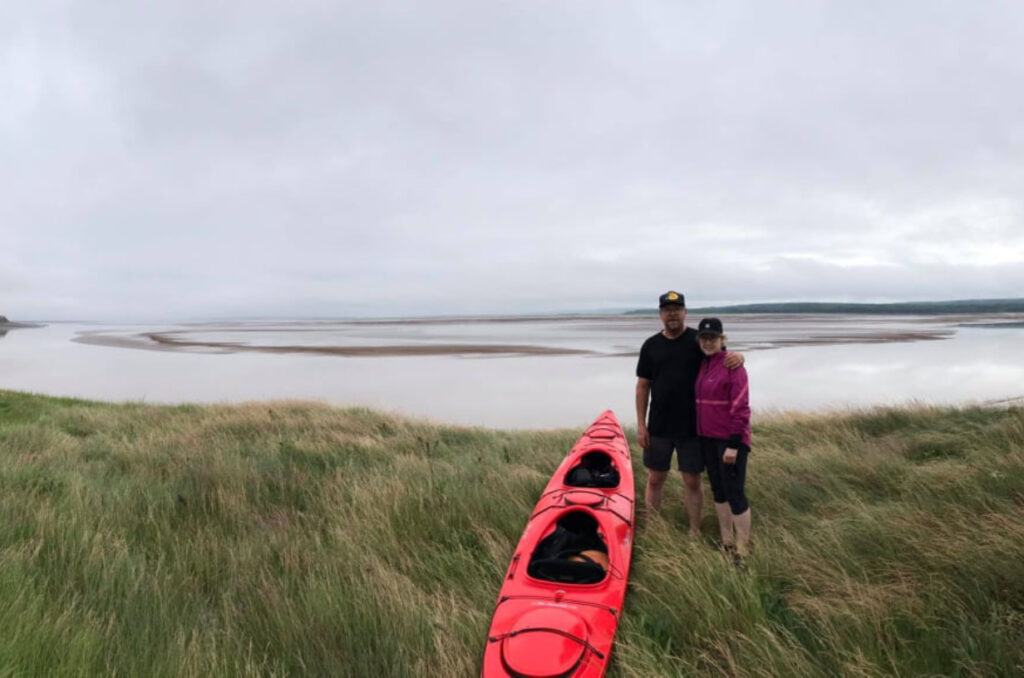 Kevin Anderson and Vallie Stearns stand beside their tandem kayak on the shores of the Maccan river in Nova Scotia. In the background are bay of Fundy tidal flats awaiting the tidal bore. 