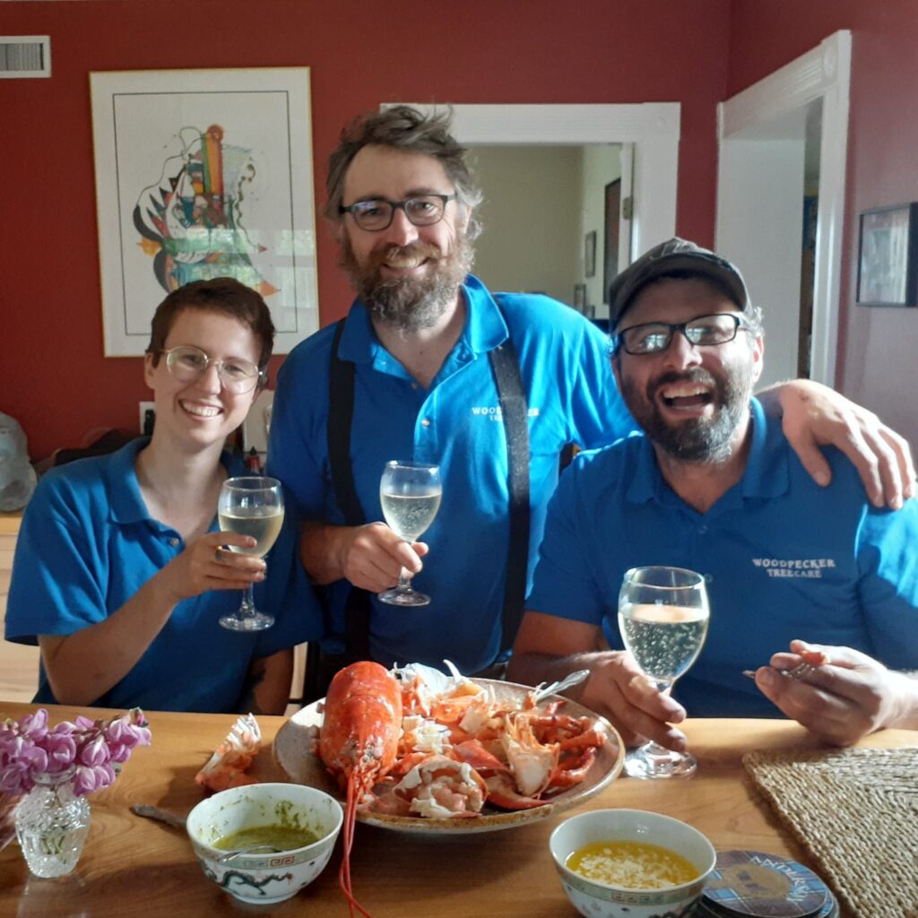 Meg, John, and Rory raise their glasses. A lobster is on the counter in front of them.