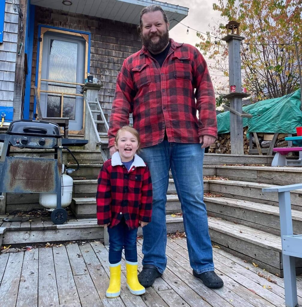 Dave Carey stands with his daughter Amelia. They are wearing matching red plaid.